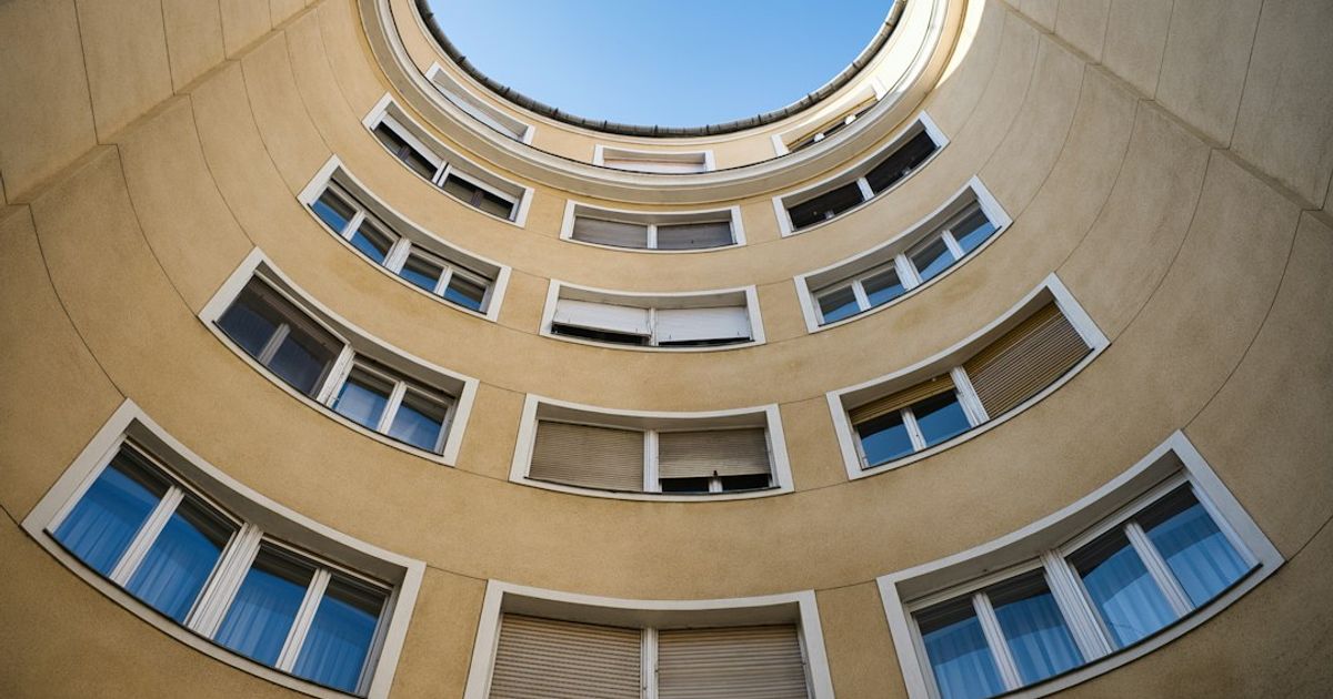Íves, sárga homlokzatú lakóház sok ablakkal, kék ég alatt (Fotó: Maksim Shutov, Unsplash)